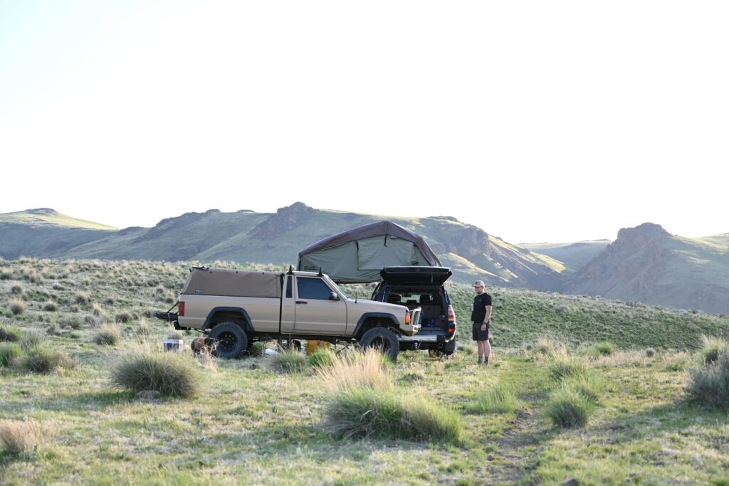 4x4 truck with roof tent set up in picturesque grassland, ideal for overlanding enthusiasts.