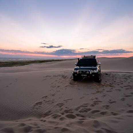 A 4x4 vehicle captures the spirit of adventure against a stunning desert sunset in Australia.