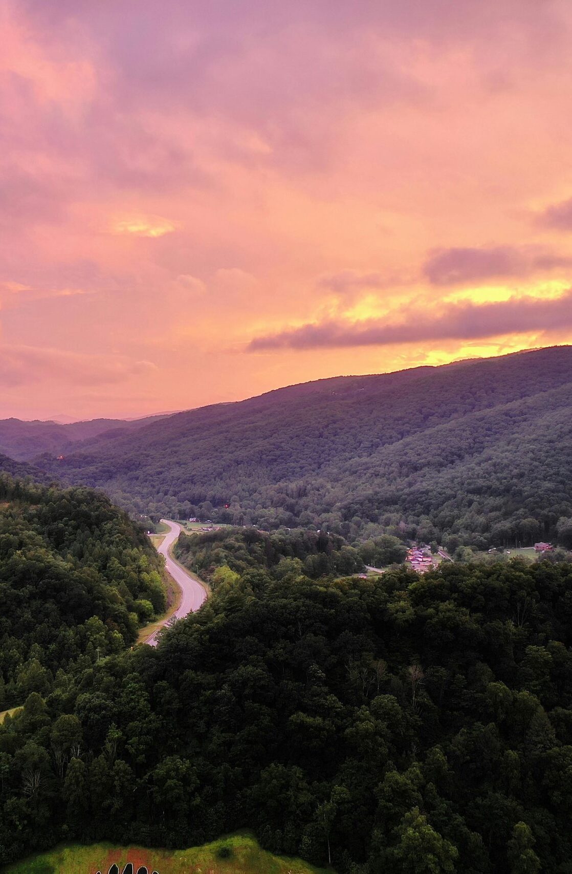 A breathtaking aerial view of sunset over lush Appalachian mountains and winding road in Harlan, KY.