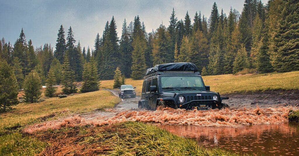 Jeep traversing a muddy off-road trail in a scenic forest. Ideal for adventure enthusiasts.