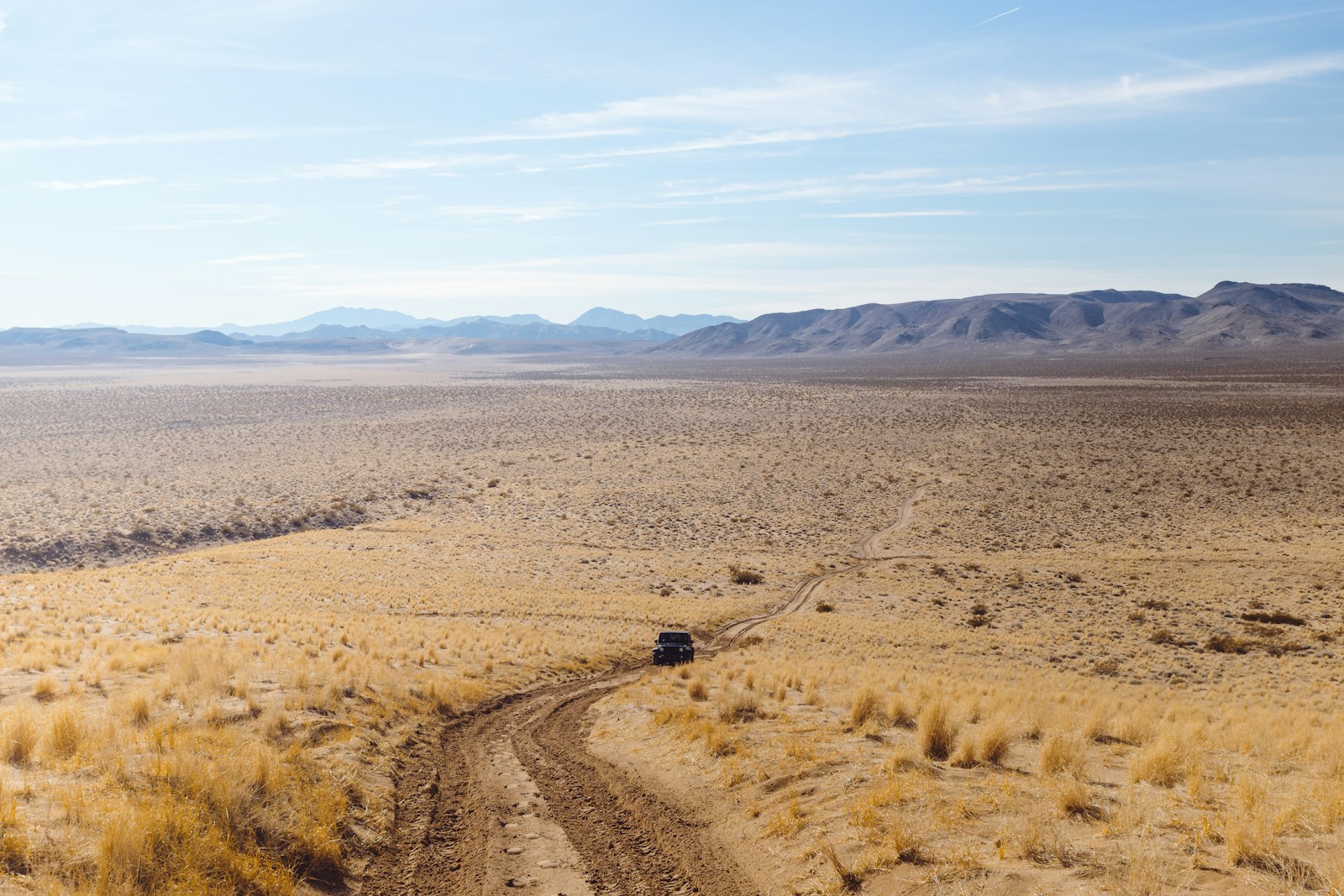 wide-angle photography of black vehicle traveling on desert during daytime