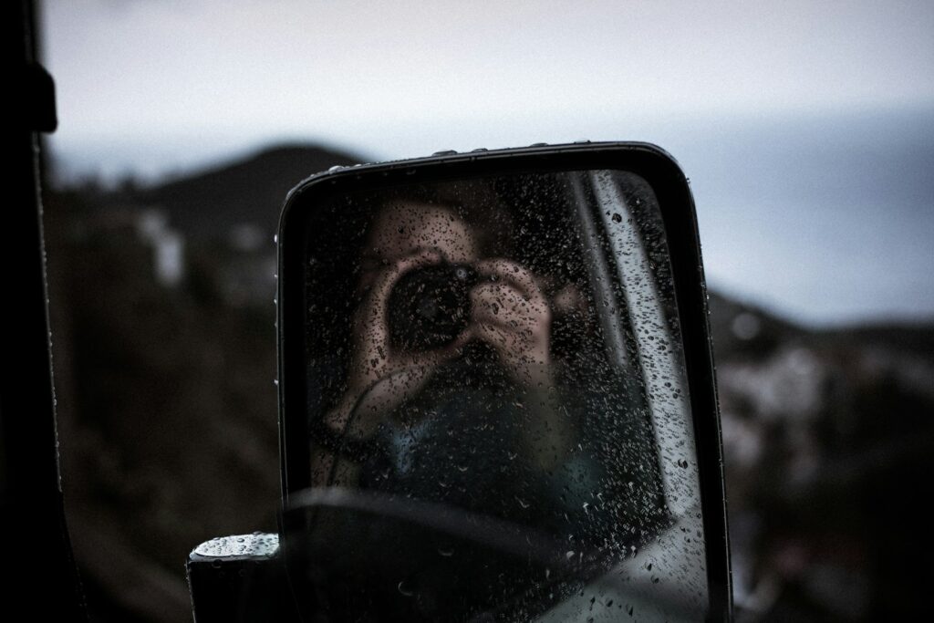 reflection of person using DSLR camera on vehicle side mirror Photo by Fabio Jock