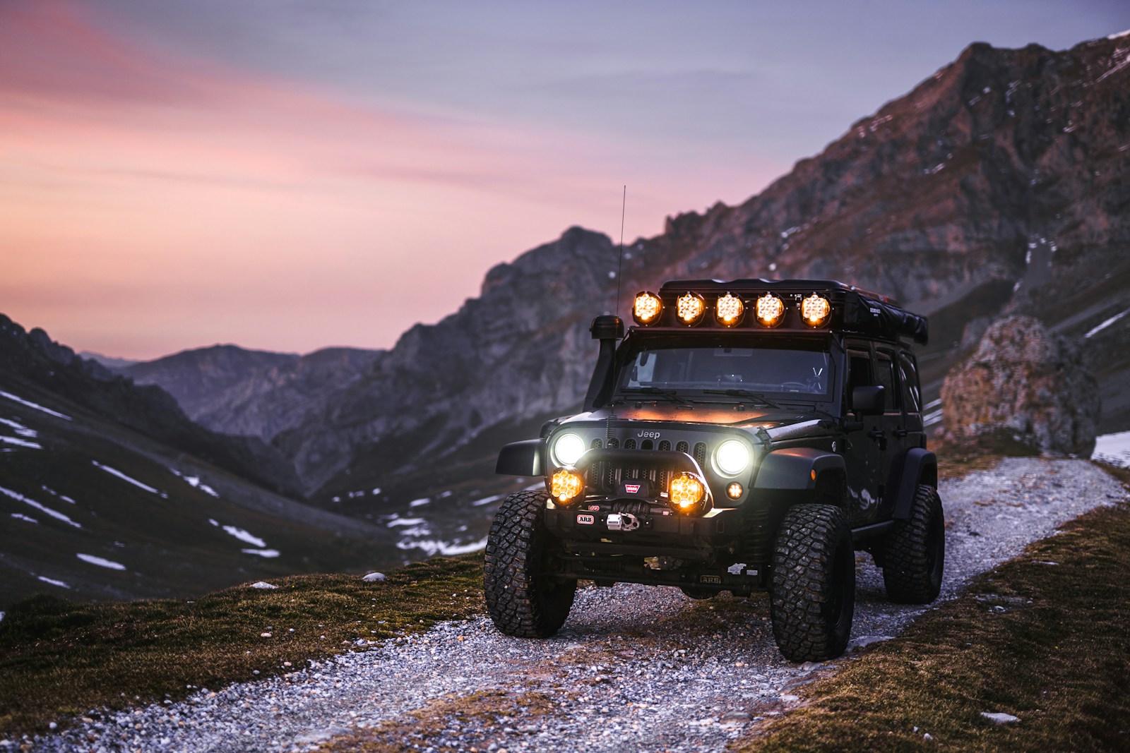 Jeep traverses a mountain trail at dusk.