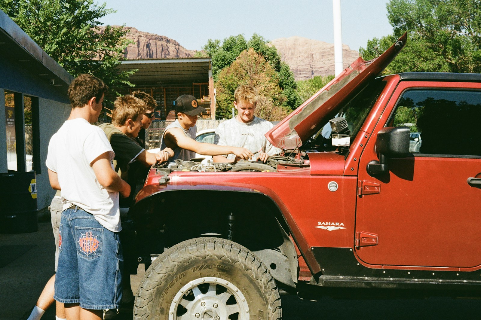 Group of friends working on a red jeep engine