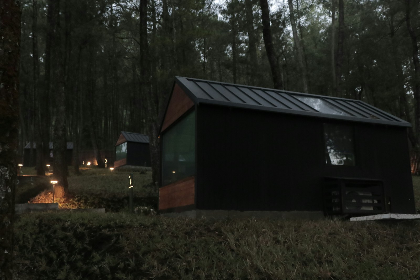 a small cabin in the woods with lights on