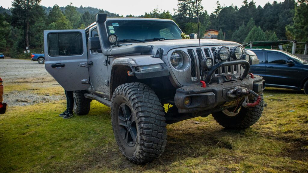 a jeep is parked in the grass near other cars