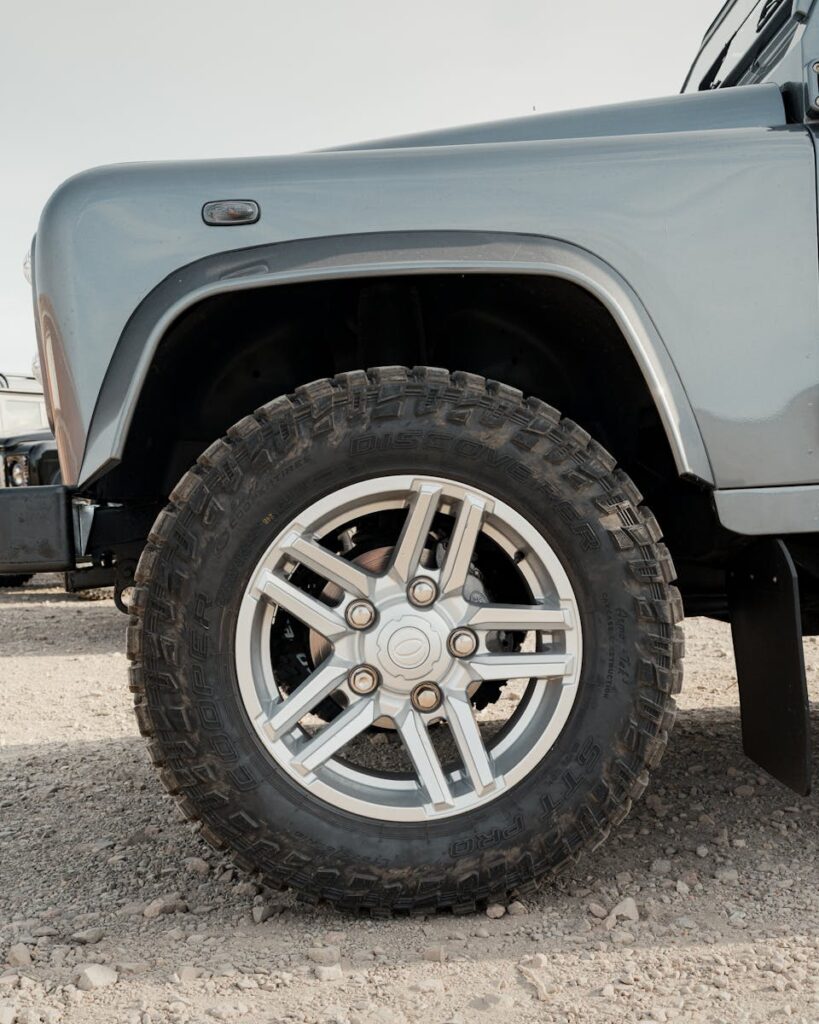 Detailed view of a rugged off-road vehicle tire on a gravel surface, showcasing tread design.