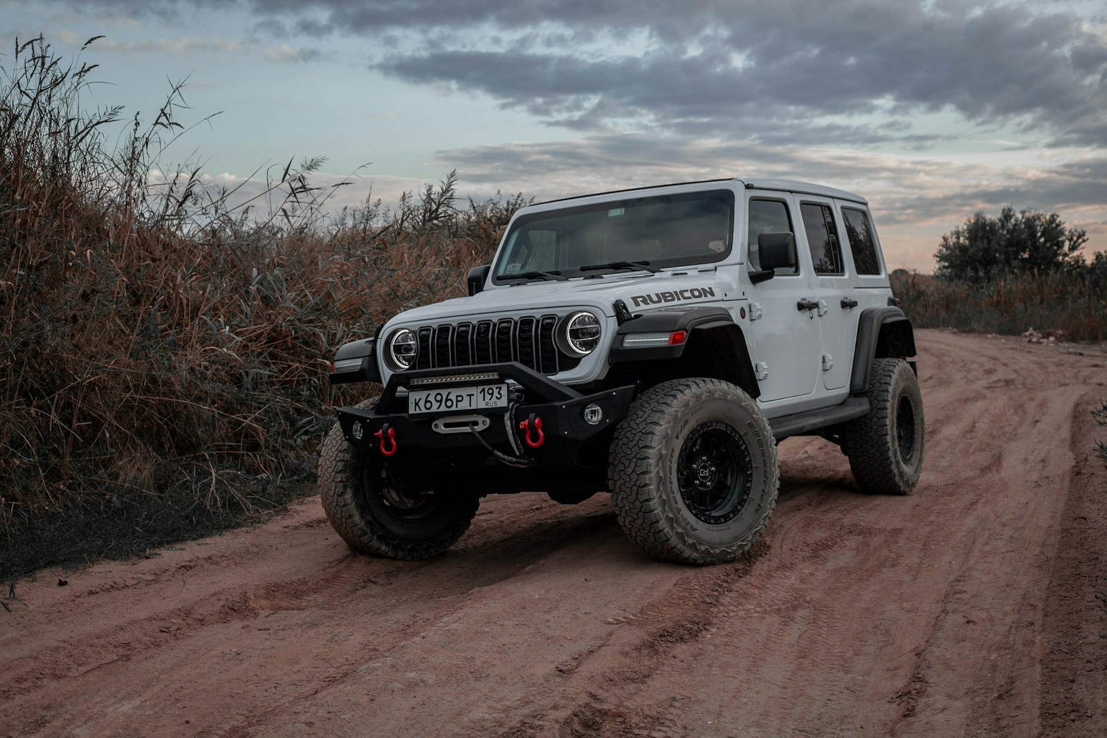 White jeep wrangler rubicon on a dirt road payload